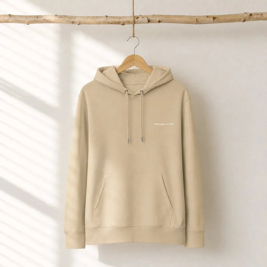 Sweat à capuche bio Massage Is Life, beige, suspendu sur cintre en bois, design minimaliste et doux.