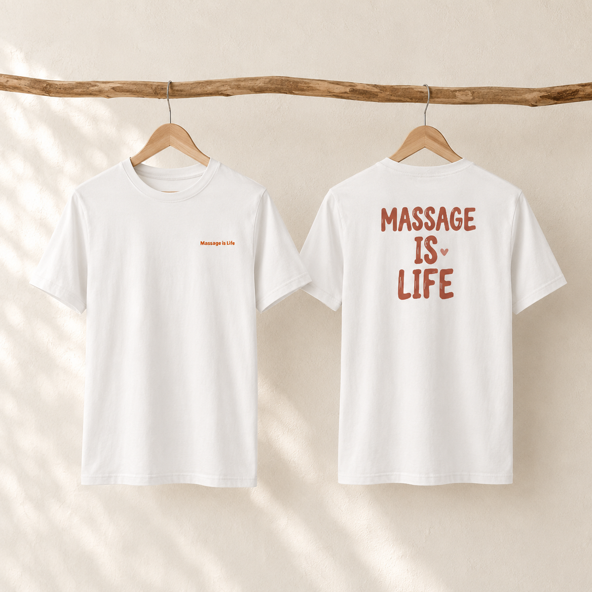 T-shirt blanc bio Massage Is Life, dos et face, suspendu sur cintre en bois, design doux et lifestyle
