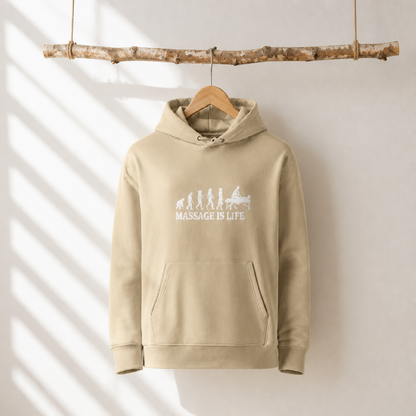 Sweat à capuche bio beige avec imprimé 'Massage Is Life' et évolution humoristique, suspendu à une branche naturelle