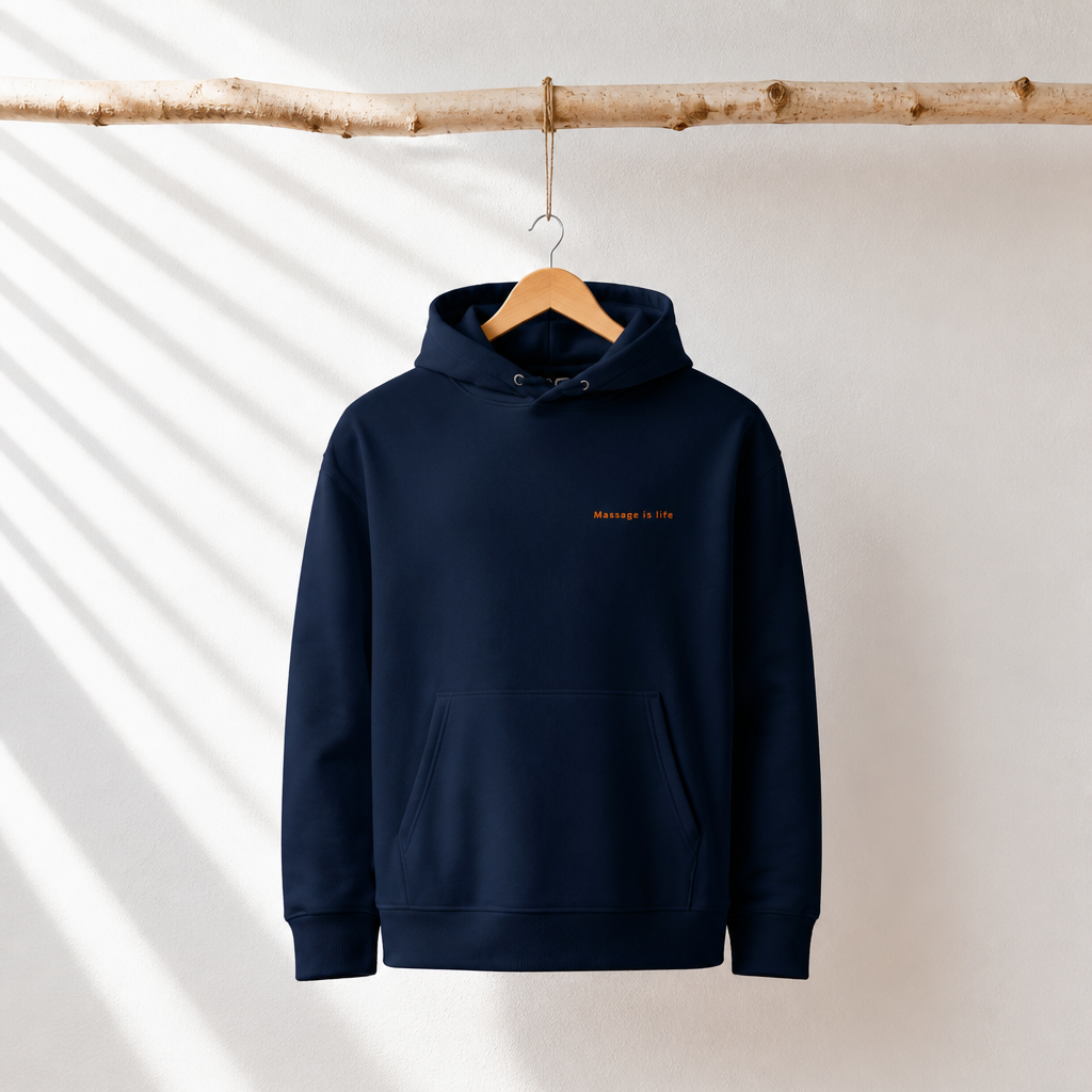Sweat à capuche bio bleu marine avec inscription 'Massage is life', suspendu à une branche en bois