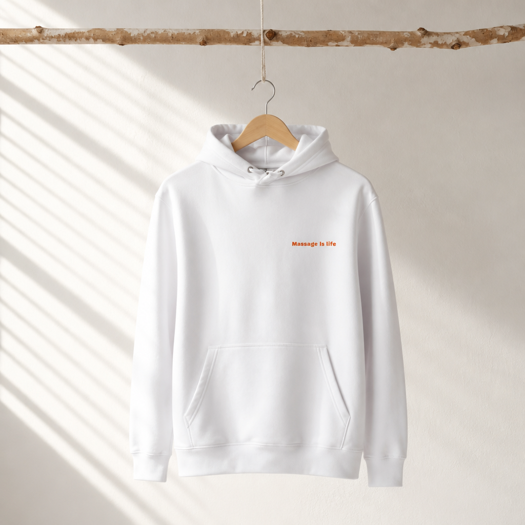 Sweat à capuche blanc bio avec inscription 'Massage Is Life', suspendu sur cintre en bois, lumière naturelle