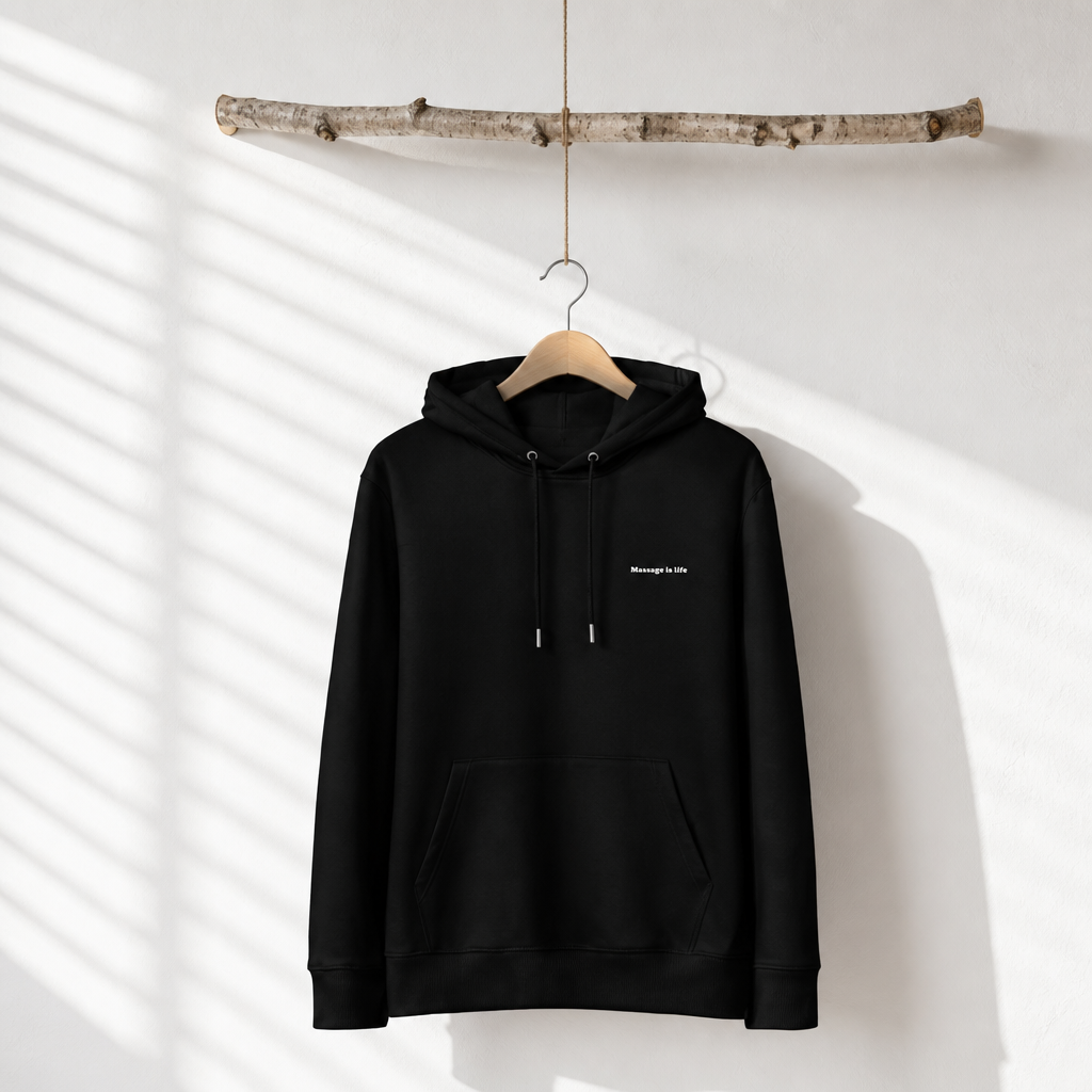 Sweat à capuche noir bio 'Massage is life', suspendu sur cintre en bois, style bien-être et lifestyle