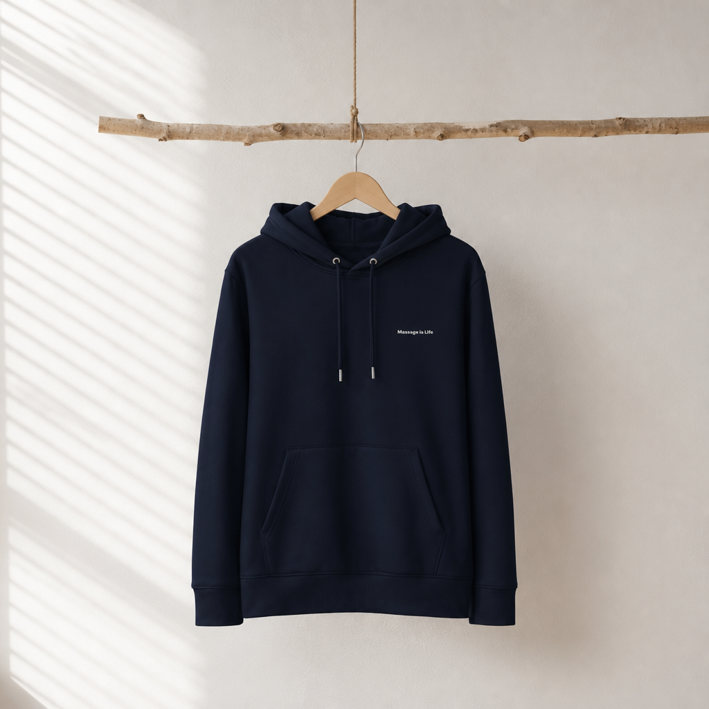 Sweat à capuche bio navy avec logo 'Massage Is Life', suspendu sur cintre en bois, lumière naturelle