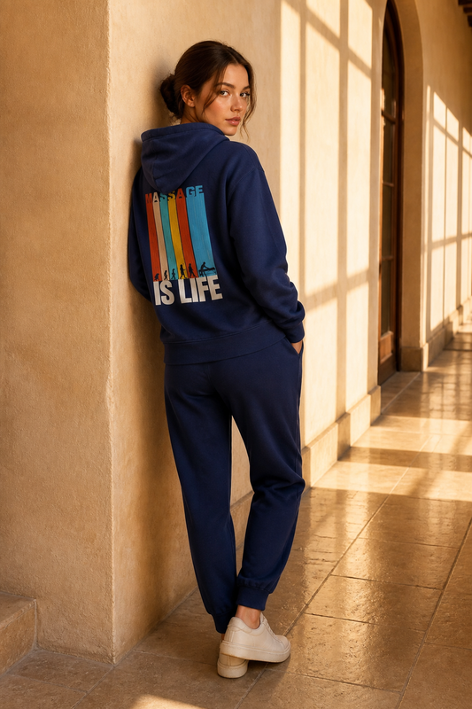 Sweat-shirt bio bleu marine 'Massage Is Life' avec imprimé rétro, porté avec pantalon assorti dans un couloir lumineux
