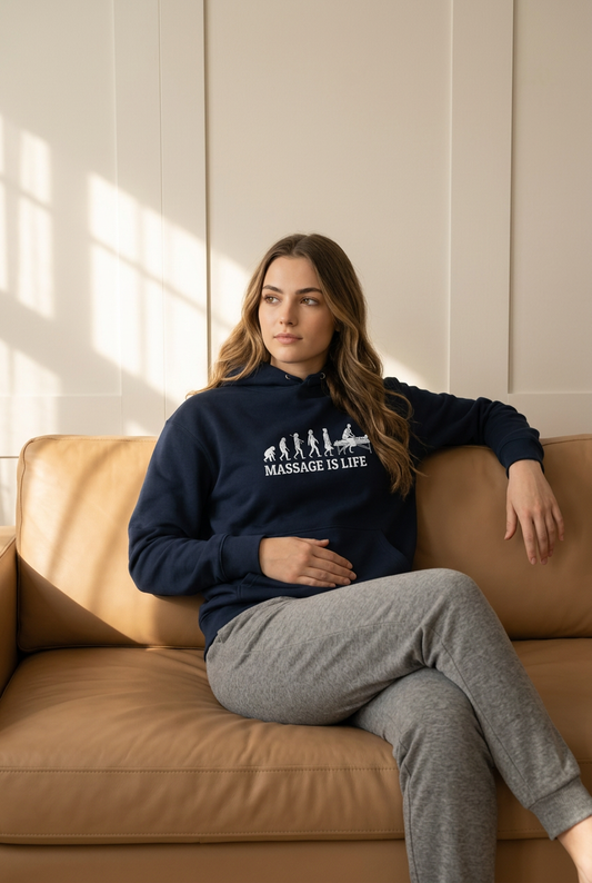 Hoodie bio Massage Is Life avec imprimé évolution, porté sur canapé beige, style bien-être et lifestyle