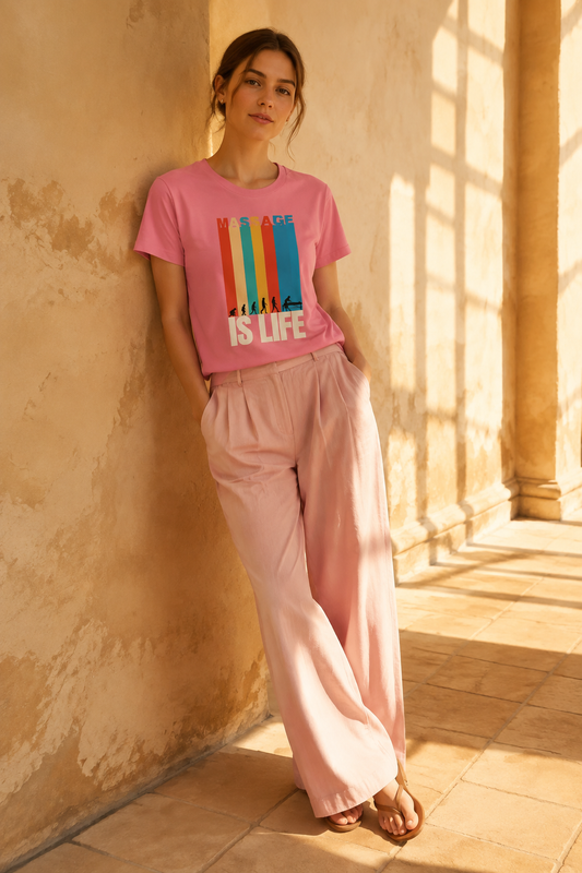 T-shirt rose bio Massage Is Life avec imprimé coloré, porté avec pantalon large dans un cadre lumineux